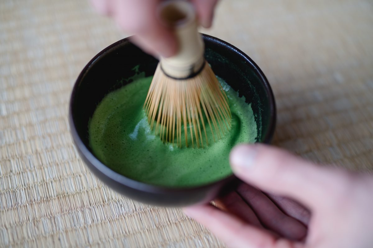 A bowl of tea, whiskes with chasen bamboo tea whisking green matcha